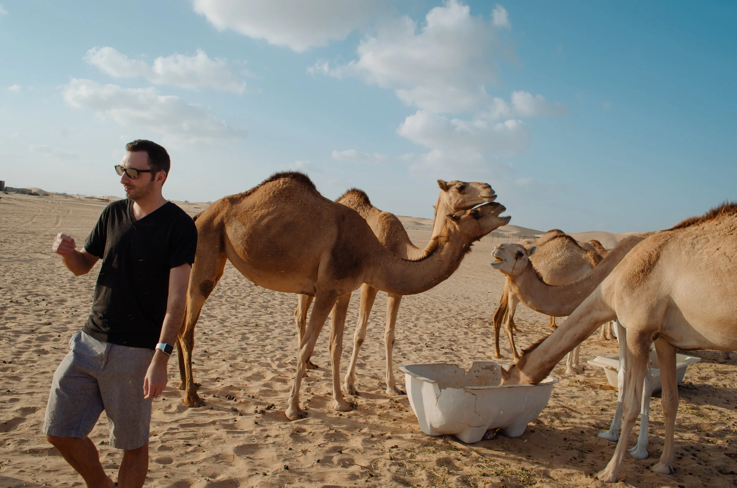 Justin walking beside a group of camels in the desert